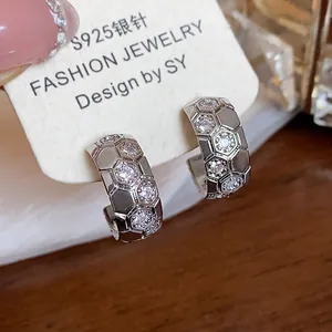 Macro view of 18k gold plated C-shaped earrings with honeycomb zircon details