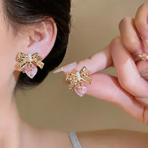 Detail shot of fairy-style pink heart bow clip-on earrings with pearls on an ear.