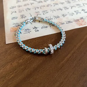 Close-up of a blue and silver braided bracelet with zirconia rings in a vintage setting.
