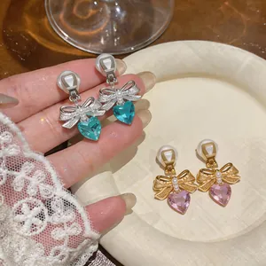 Detail view of bow and heart-shaped crystal clip-on earrings in gold and silver colors