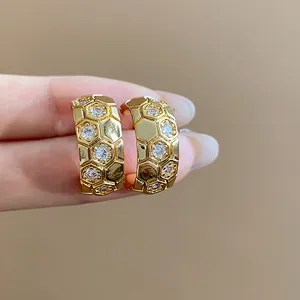 Detail view of 18k gold plated C-shaped earrings with honeycomb zircon pattern