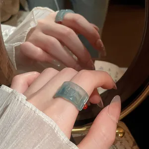Close-up of a vintage light blue resin ring with an embossed 'Fu' character design