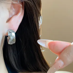 Close-up of silver C-shaped stud earrings with sparkling zircon honeycomb pattern detail