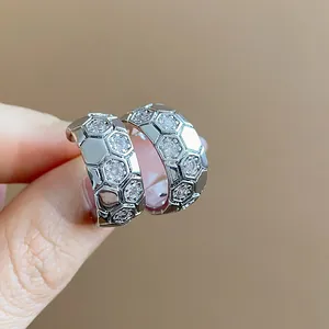 Detailed close-up of C-shaped hoop earrings with hexagonal honeycomb zircon pattern