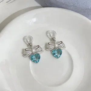 Detailed close-up of elegant bow heart clip-on earrings with pearl and blue crystal drops
