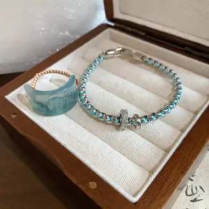 Detail view of retro resin Fortune ring and blue woven bracelet set in wooden box