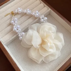 Elegante collana con fiore in chiffon color crema e perle bianche su vassoio gioielli
