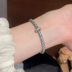 Macro view of a chic blue and silver woven bracelet featuring a crystal charm on a woman's wrist.