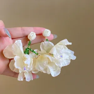 Close-up detail shot of sweet white mesh flower earrings with green crystal beads and rose studs