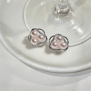 Close-up of elegant flower-shaped stud earrings with pink pearls and sparkling zircons.