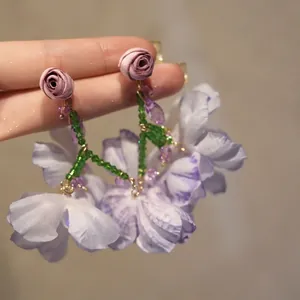 Close-up of lilac mesh flower earrings with crystal beads and rose stud detail