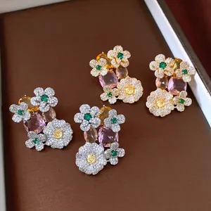 Close-up of vintage flower earrings with colorful oval crystals on brown display tray.