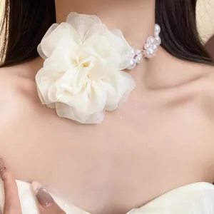 Dettaglio ravvicinato di un elegante girocollo con fiori in chiffon e perle su una modella