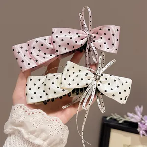 Gros plan de barrettes à nœuds en ruban à pois rose et blanc avec détails en dentelle