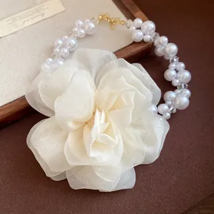 Dettaglio di elegante collana a fiori in chiffon crema con lucenti perle bianche