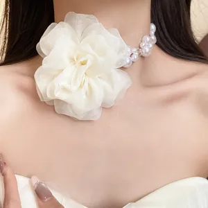 Primo piano di un'elegante collana con fiore in chiffon bianco e perle sul collo.