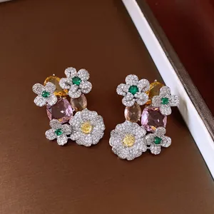 Macro shot of vintage floral stud earrings with pink, green, and yellow cubic zirconia stones.