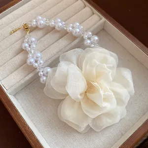Vista dettagliata del fiore in chiffon crema e collana di perle in portagioie