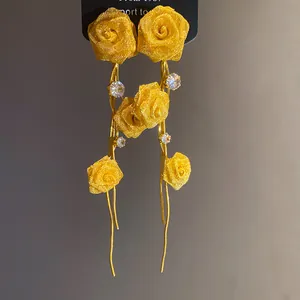 Detailansicht eleganter gelber Stoffrosen-Quastenohrringe mit funkelnden Strasssteinen.
