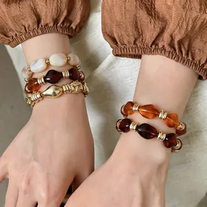 Nahaufnahme von geometrischen Retro-Armbändern aus Harz mit Goldperlen an Modelhandgelenken