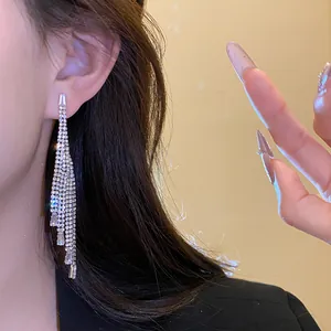 Close-up detail of elegant silver-colored zirconia long tassel dangle earrings on a model