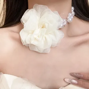 Dettaglio macro del fiore in chiffon bianco e delle perle su una collana choker floreale