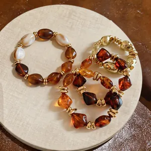 Nahaufnahme von vintage elastischen Armbändern mit geometrischen Bernstein- und Goldperlen.