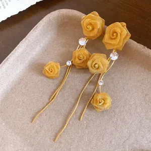 Detailansicht eleganter goldener Netzrosen-Ohrringe mit langen Quasten.