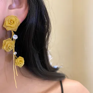 Nahaufnahme eleganter goldener Netz-Rosenohrringe mit Quasten, die am Ohr getragen werden