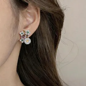 Close-up detail of vintage floral stud earrings with colorful zircons on ear.