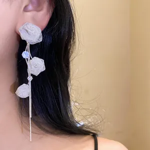 Nahaufnahme eines französischen Rosen-Quasten-Ohrrings mit Mesh-Blütenblättern und Kristallen.