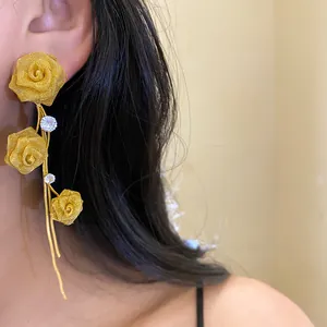 Detailaufnahme eleganter goldener Rosen-Quastenohrringe mit feiner Netztextur und Strass