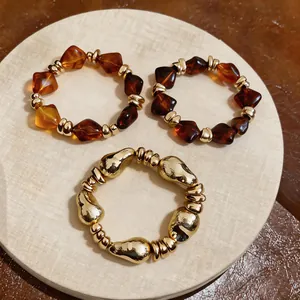 Detailansicht von drei elastischen Vintage-Armbändern mit bernsteinfarbenen Goldperlen.