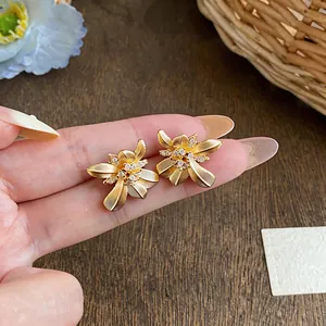 Primer plano detallado de pendientes vintage de flor dorada con piedras de circonita.