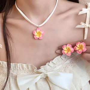 Detailweergave van de Hawaiiaanse Plumeria bloemenketting en oorbellen set op een model