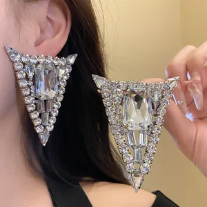 Detalle macro de pendientes triangulares plateados grandes con pedrería brillante