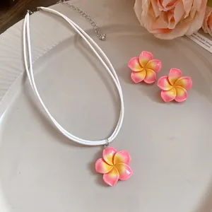 Gedetailleerd close-up van Hawaïaanse plumeria bloem ketting en oorbellen set op bord