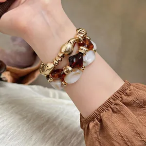 Nahaufnahme von geometrischen Retro-Armbändern mit Gold-, Bernstein- und Marmorperlen