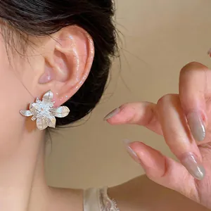 Primer plano detallado de elegantes pendientes de flor plateados con circón en oreja
