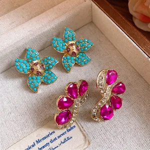 Vintage flower earrings with turquoise beads and vibrant pink crystal petals in a box.