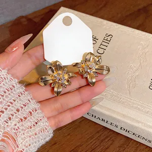Detalle de pendientes de flores doradas de estilo vintage con brillantes circonitas