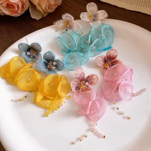 Elegant detail view of colorful chiffon flower tassel earrings on a white ceramic plate