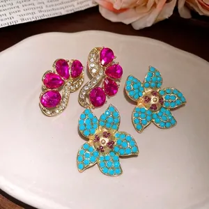 Vintage style floral stud earrings with pink rhinestones and turquoise beads on a dish