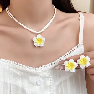Detailopname van witte en gele Hawaiiaanse frangipani bloemen ketting en oorbellen set