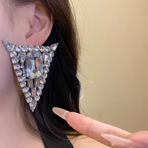 Primer plano de elegantes pendientes triangulares de strass con aguja de plata esterlina.