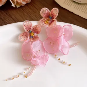 Close-up detail showing the intricate pink chiffon flower tassel earrings with beads