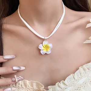 Zoete geel-witte plumeria bloem hanger ketting aan een zacht wit fluwelen koord