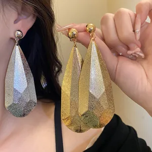 Dettaglio di eleganti orecchini a goccia in metallo oro e argento con texture