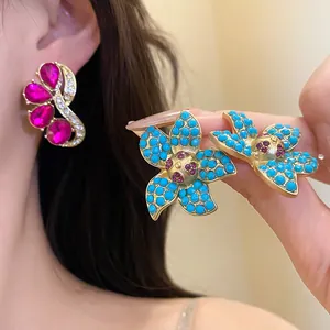 Macro view of vintage gold-tone floral and abstract rhinestone earrings on model