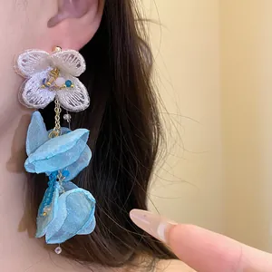 Detailed macro view of elegant white chiffon flower tassel earrings with blue petals